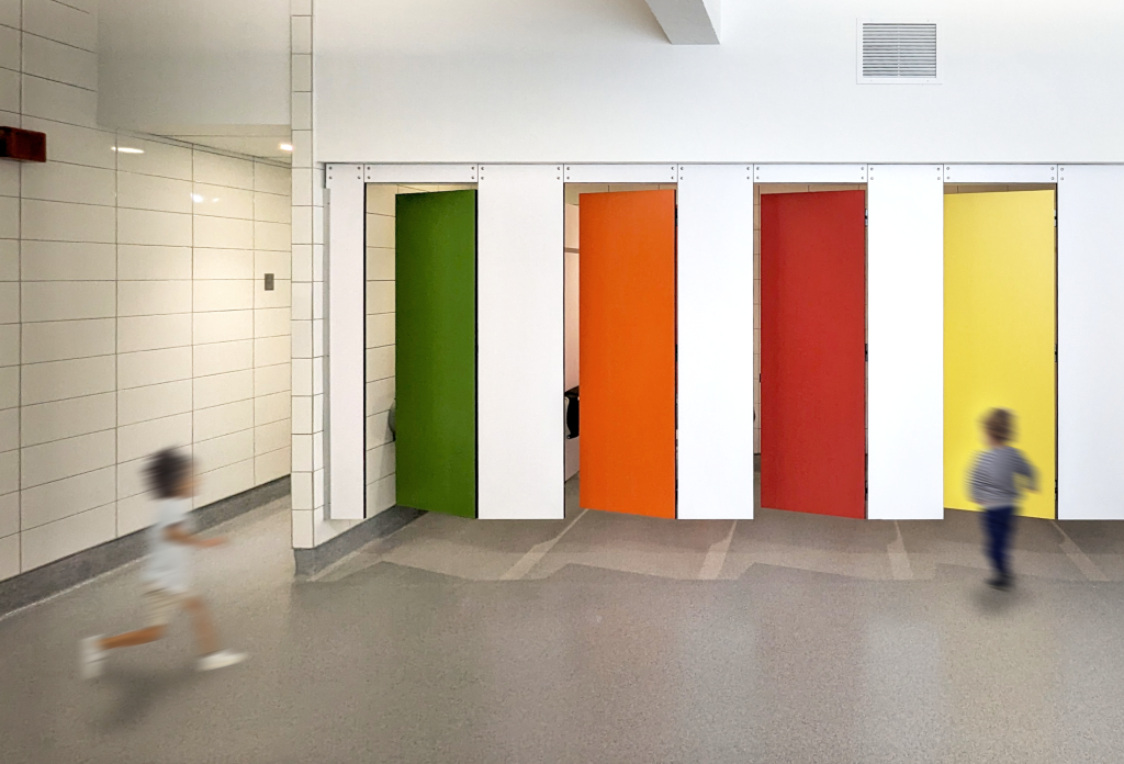 A public bathroom interior with a row of five brightly coloured bathroom stall doors, each in a different colour: green, orange, red, yellow, and blue. The doors are set within a white wall. Two young children, slightly blurred from motion, are running across the foreground of the image.